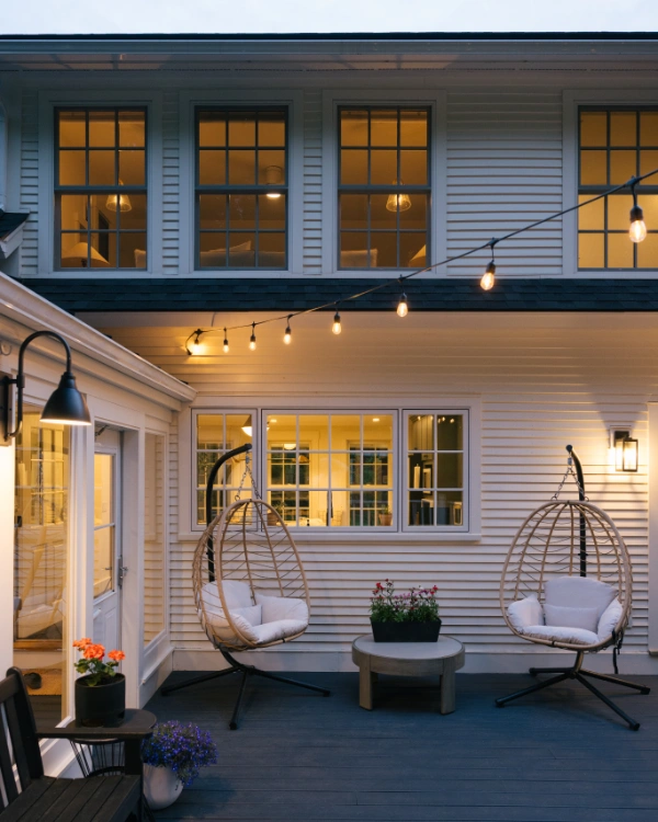 Outdoor deck with hanging egg chairs, string lights, and seating area